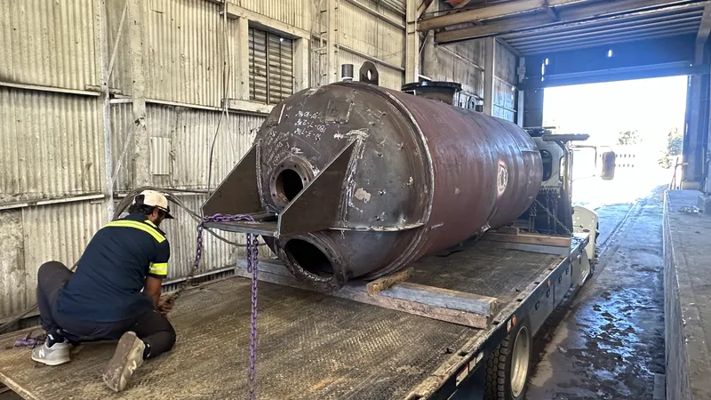 Ramco employee chaining a finished tank to a flatbed trailer at the shop door