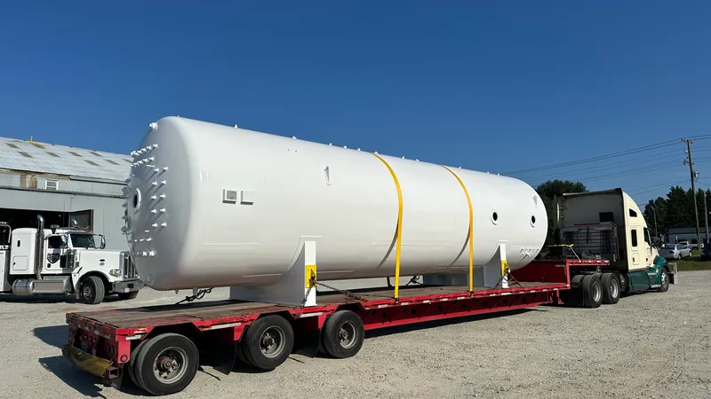 Painted horizontal pressure vessel loaded on a lowboy trailer, ready to ship