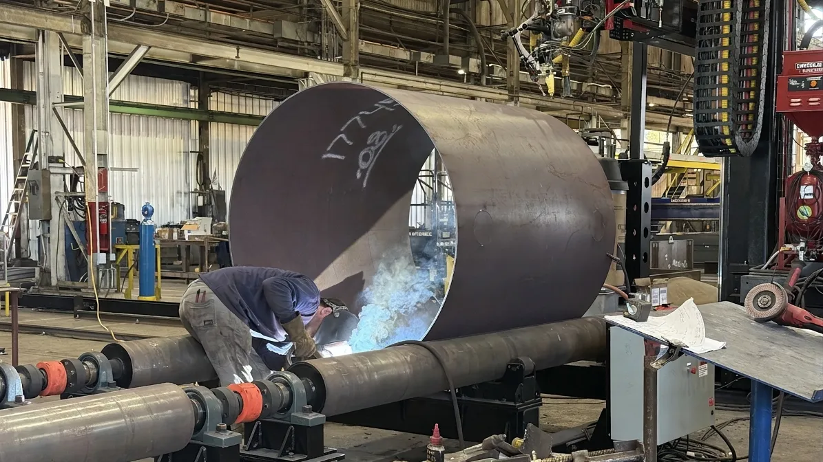 Ramco welder working inside a rolled steel shell on turning rolls in the shop